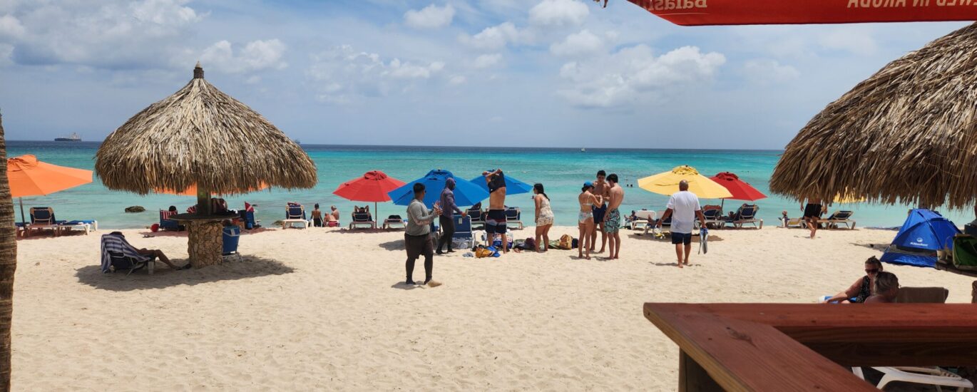 A breathtaking view of Arashi Park and Beach in Aruba, featuring pristine white sand, turquoise water, and a clear sunny sky.