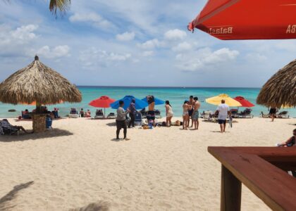 A breathtaking view of Arashi Park and Beach in Aruba, featuring pristine white sand, turquoise water, and a clear sunny sky.